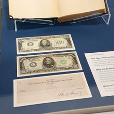 High denomination US currencies on view alongside check signed by JFK and autographed first copy of the first edition of 