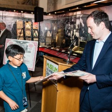 Alexander Burns hands out stock certificates to students at the launch of the Free Saturday program.